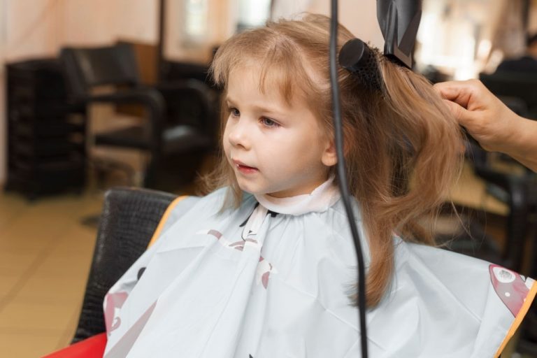small red-haired girl 4 years old in a beauty salon. hair styling process