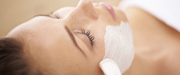 Closeup of a beauty therapist applying a face mask to a client