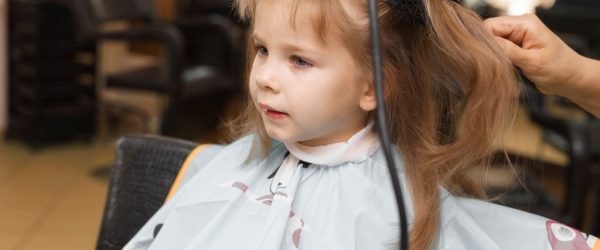 small red-haired girl 4 years old in a beauty salon. hair styling process